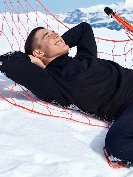 Franjo von Allmen reclining in the nets on a ski slope.