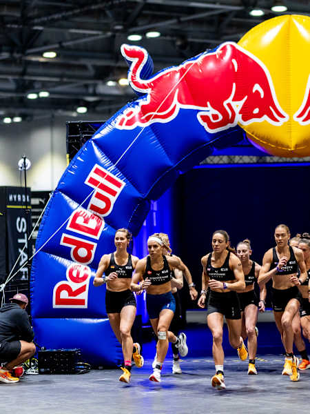 HYROX Elite 15 women charging forward under a Red Bull arch