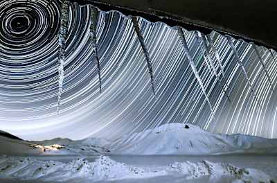 Stars moving on the sky and shining through some icicles.