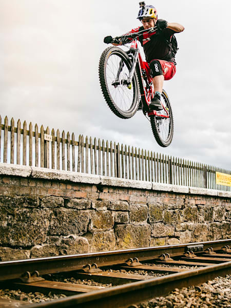 Le trialiste Danny MacAskill en plein saut en vélo trial sur la voie ferrée.