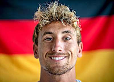 Foto-Porträt des Surf-Profis Leon Glatzer vor der deutshen Nationalflagge.