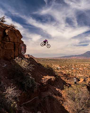 Chelsea Kimball soars off a cliff edge on her mountain bike during the women's final at the extreme Red Bull Rampage freeride event in the rugged Utah desert landscape, 2024