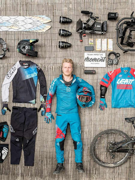 Rider stands among downhill clothing and protection and camera kit during shoot for Leatt DH collection 2018.