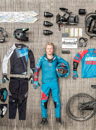 Rider stands among downhill clothing and protection and camera kit during shoot for Leatt DH collection 2018.