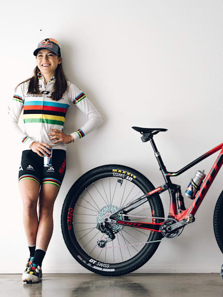 Kate Courtney poses for a photo alongside her bike.