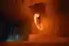 Jesper Tjäder is in a cave on skis jumping through a hoop on fire.