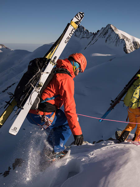 Climbers roped together walk across snow covered mountain ridge in Switzerland.