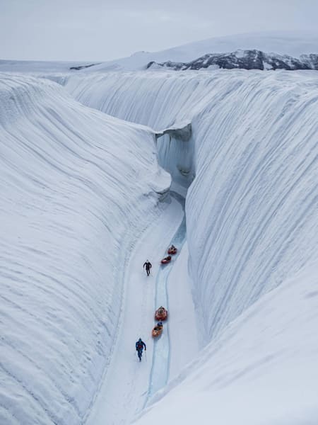 Adventurers tow kayaks through the ice