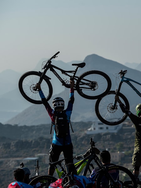 Competitors hold up their bikes in celebration.