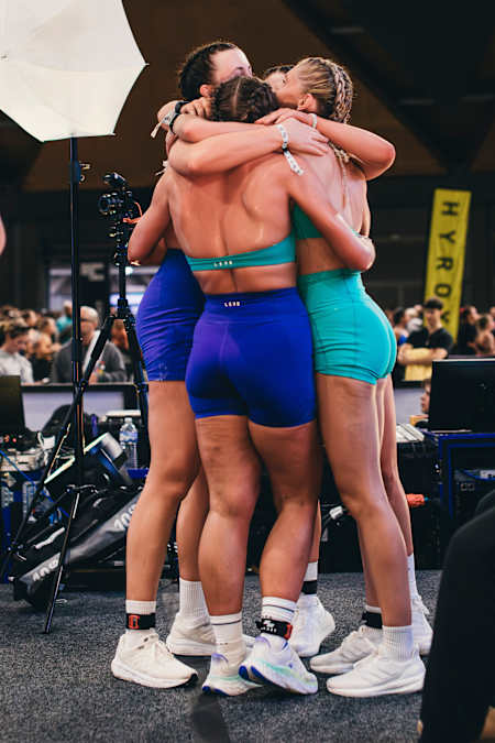 In 2024, two Hyrox Sydney participants embrace after completing the fitness challenge, wearing vibrant blue and teal athletic outfits