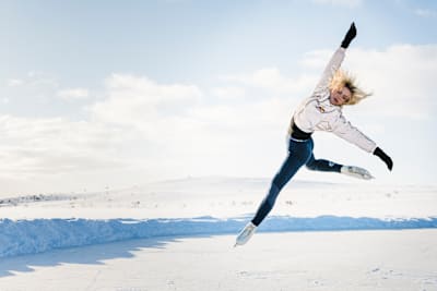 La patineuse artistique finlandaise Emmi Peltonen s’élance dans les airs sur une patinoire en plein cœur de l’hiver.