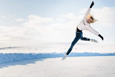 La patineuse artistique finlandaise Emmi Peltonen s’élance dans les airs sur une patinoire en plein cœur de l’hiver.