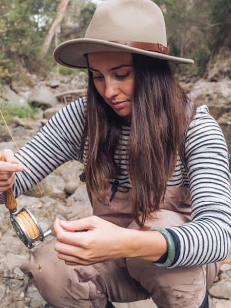 Setting up a fishing rod next to a rocky stream.