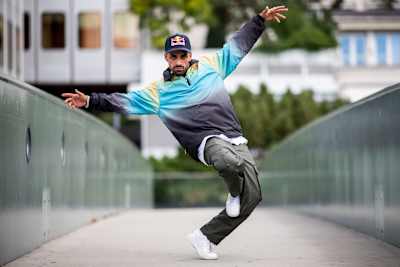 Majid stands on one leg with hands spread out.