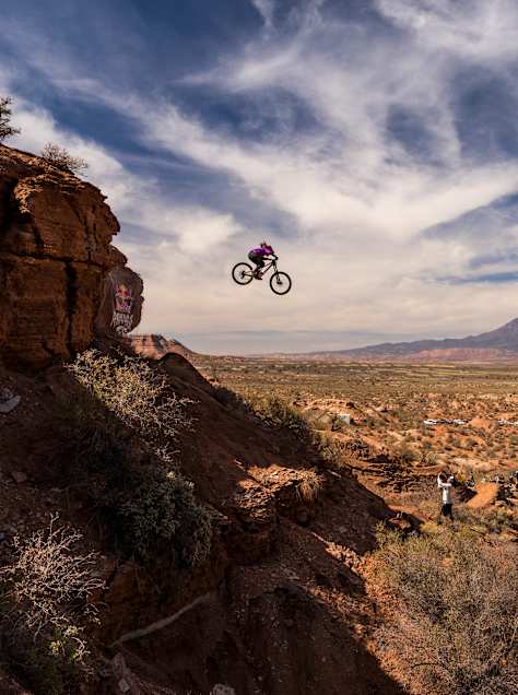 Chelsea Kimball soars off a cliff edge on her mountain bike during the women's final at the extreme Red Bull Rampage freeride event in the rugged Utah desert landscape, 2024