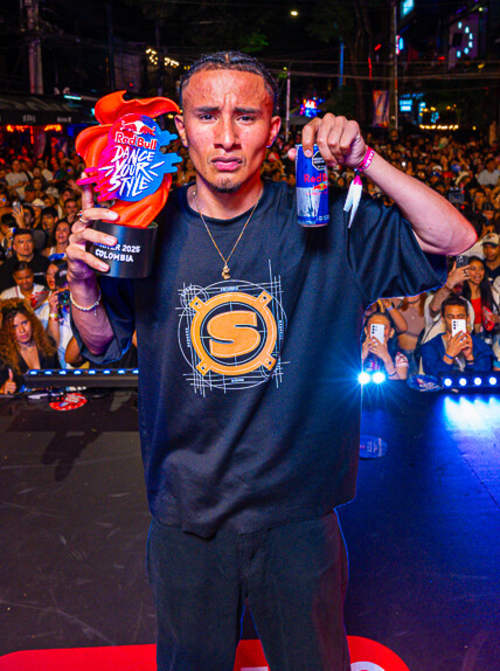 Erre Caserio celebrates winning the Red Bull Dance Your Style National Final 2025 in Medellin, Colombia, holding the trophy high on stage before a cheering crowd