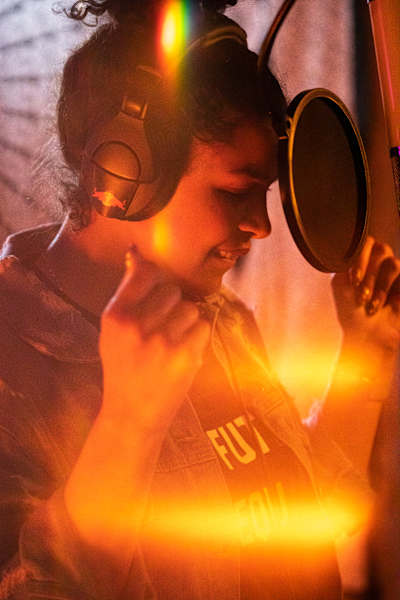 A photo of US soul-pop singer Jordin Sparks recording in the studio, singing into a mic.