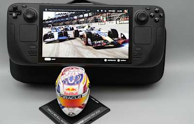 Bild zeigt das Steam Deck OLED mit dem Spiel F1 23 und einem Modell des Helmes von Formel-1-Piloten Max Verstappen