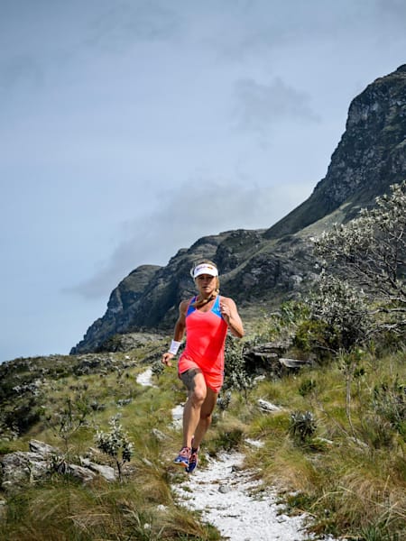 Running down a singletrack trail with mountain in background.