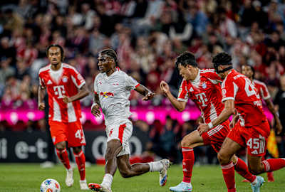Ezechiel Banzuzi défend le ballon contre plusieurs adversaires du FC Bayern.