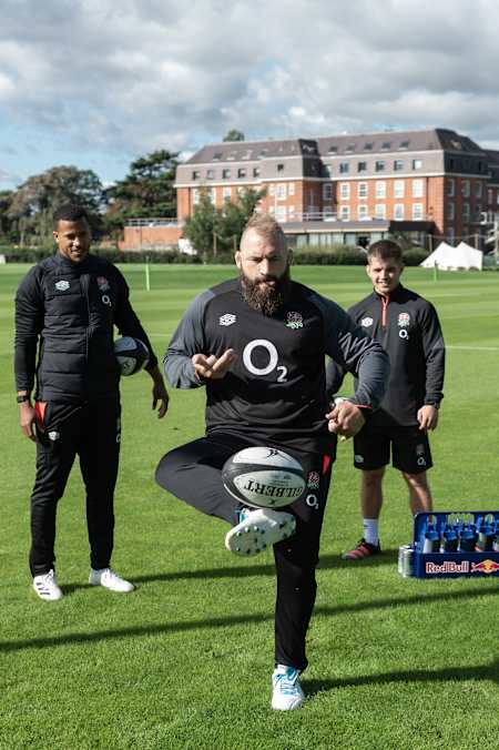 Joe Marler juggles the ball as Anthony Watson and Harry Randall look on during the England Rugby Open Training Session at The Lensbury Resort in London, United Kingdom on July 14, 2021