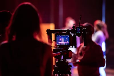 A cameraperson films dancers on the shoot of a video production in a studio.