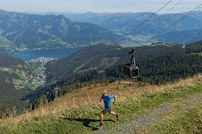 Trail runner passes a cablecar in the mountains around Zell am See.