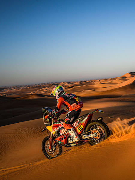 A photo of Luciano Benavides with a helicopter in the background at the 2020 Dakar.