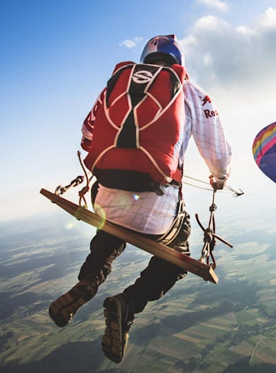 A member of the Red Bull Skydive team riding on the world's biggest rope swing strung between two hot air balloons high above Austria