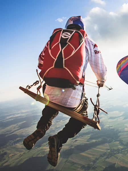 A member of the Red Bull Skydive team riding on the world's biggest rope swing strung between two hot air balloons high above Austria