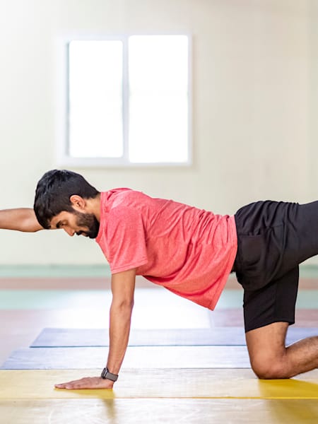 Srikanth Kidambi performs a stretch while working out in a gym.