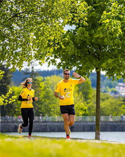 Účastníci se prohánějí po trati během Red Bull Wings for Life World Runu 2025 v Jablonci nad Nisou v České republice, obklopeni svěží jarní krajinou