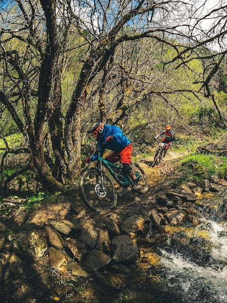 Riders disfrutando del sendero al lado del río en La Pinilla Bike Park.