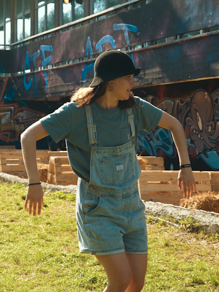 B-Girl AT dancing with grafitti and other participants in the background at Catch the Flava Camp in Krakow, Poland.