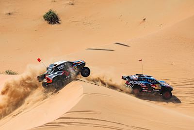 Dos coches se enfrentan a las dunas del desierto en el rally raid Dakar.