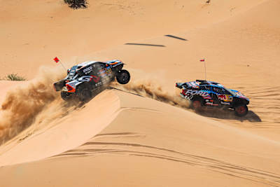 Dos coches se enfrentan a las dunas del desierto en el rally raid Dakar.