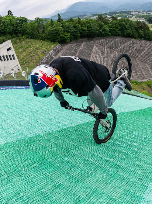 Tomomi Nishikubo begins to roll backwards down a ski jump in Hakuba, Japan in May 2026