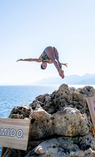 In 2024, Maria Paula Quintero cliff dives in Antalya, Turkey for Red Bull's prestigious cliff diving series amidst scenic coastal views