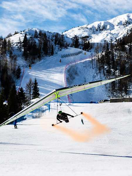 Wolfgang Siess performing a speedrun over a ski slope with his hang glider