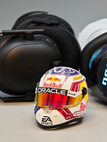 Bild zeigt eine Auswahl aktueller Gaming-Headsets von JBL, Razer, Logitech und HyperX mit einem Miniatur-Formel-1-Helm von Max Verstappen im Vordergrund.