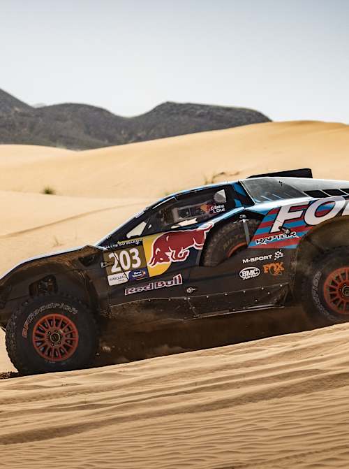 In 2024, Carlos Sainz and Lucas Cruz race a Ford Raptor rally car across Moroccan sand dunes.