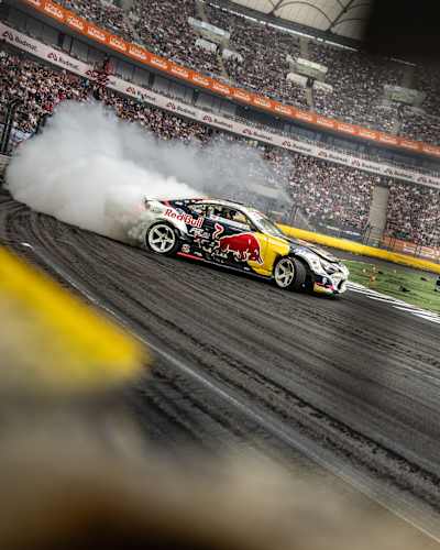 Conor Shanahan expertly drifts his Red Bull car through a smoky turn during the 2025 Red Bull Drift Masters Grand Finale in Warsaw, Poland, thrilling a packed stadium crowd.