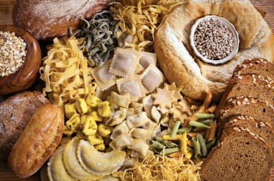 Foto von zahlreichen kohlenhydratreichen Nahrungsmitteln – von Nudeln über Brot bis zu Reis.