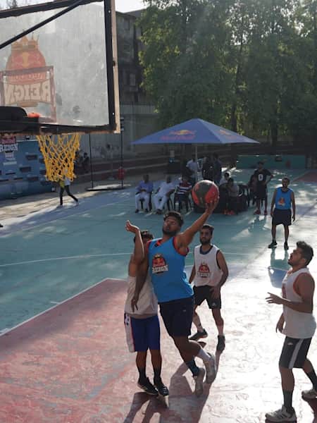 A basketballer leaps into the sky as two defenders on look him at the Red Bull Reign 2019 Delhi Qualifiers