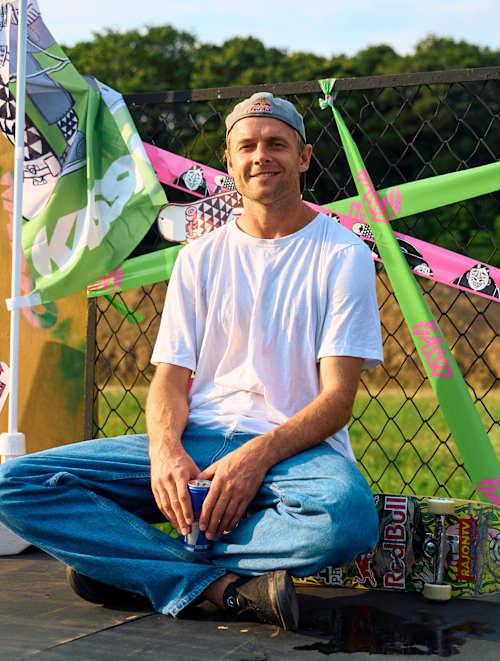 Pro skater Madars Apse pictured relaxing with his skateboard and Red Bull can at Kasso in Yokohama-shi during 2024, surrounded by bold event decor and vibrant urban style