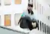 Majid is posing on a wall in front of a blurry building.