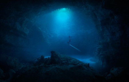 Freediver with torch seen in underwater caves in the Yucatan Peninsula of Mexico, shot by Klaus Thymann for Red Bull Illume.