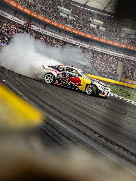 Conor Shanahan expertly drifts his Red Bull car through a smoky turn during the 2025 Red Bull Drift Masters Grand Finale in Warsaw, Poland, thrilling a packed stadium crowd.