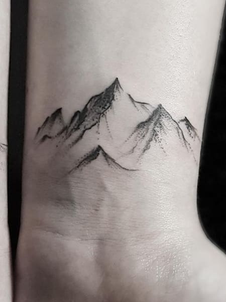 Mountain and wave tattoo on the wrists.