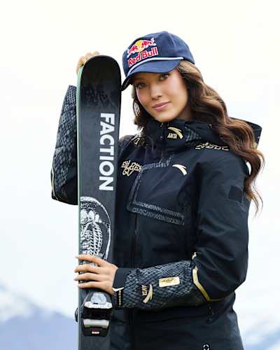Eileen Gu poses with Faction skis while wearing a Red Bull cap.